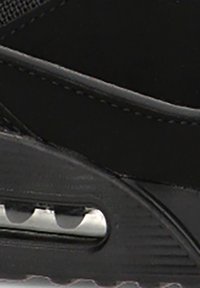 Primer plano de la suela de una zapatilla negra que muestra una cámara de aire visible y una banda de rodadura de goma texturizada para tracción.