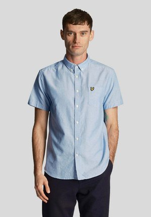 Camicia a maniche corte, di colore azzurro chiaro, con bottone e taschino sul petto, decorata con un logo a farfalla gialla. Realizzata in tessuto leggero con una finitura leggermente testurizzata.