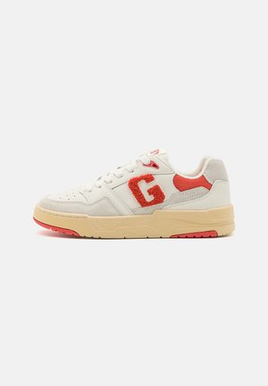 Hvid og beige sneakers med røde accenter, et stort rødt struktureret "G" på siden og beige sål med røde slidstyrsdetaljer.