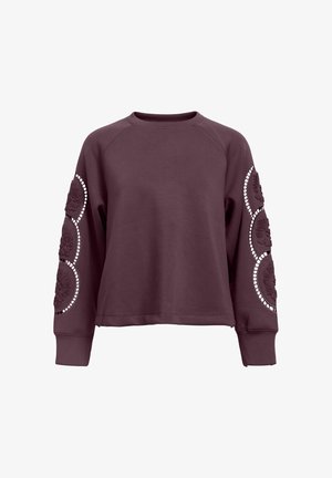 Maroon sweatshirt with raglan sleeves, featuring embossed floral patterns and circular cutouts with detailing along the sleeves.