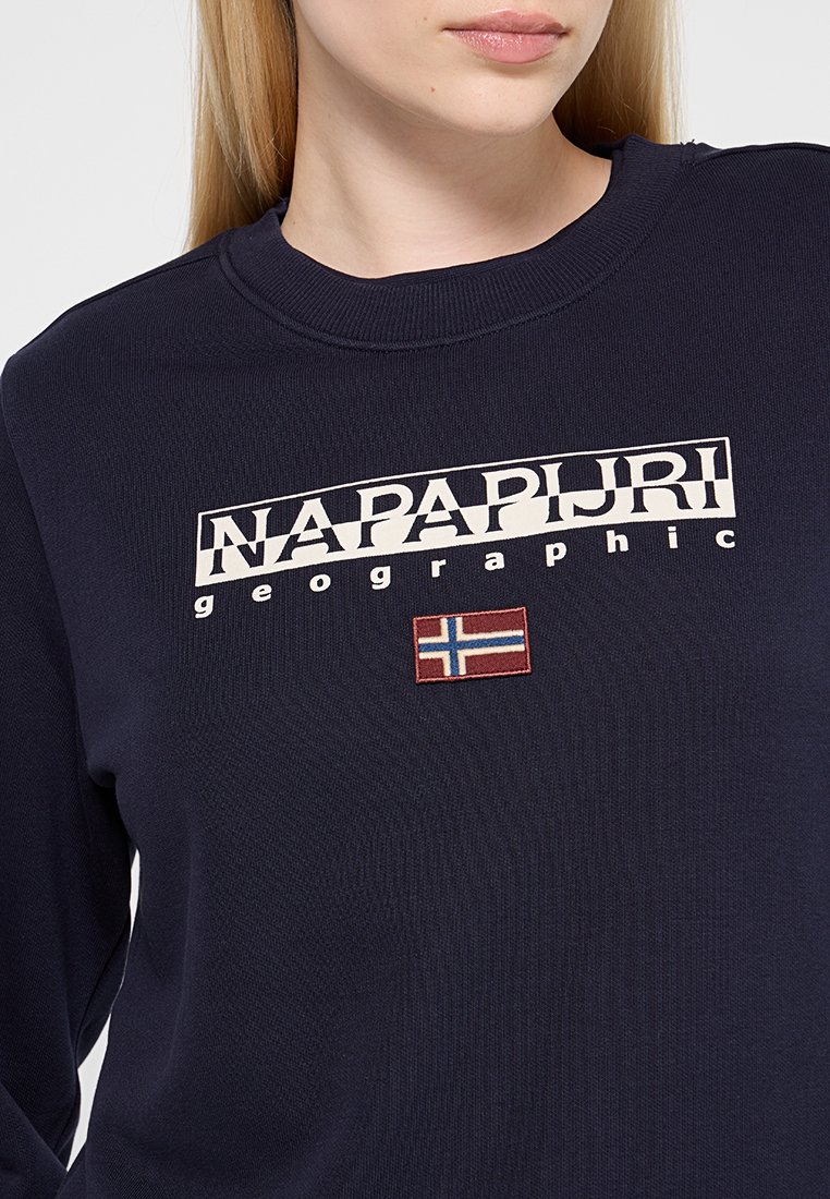 Il pullover color blu navy presenta un collo a costine, un logo frontale "NAPAPIJRI geographic" e un piccolo patch ricamato della bandiera norvegese.