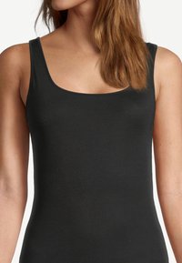Débardeur noir en matériau lisse et extensible, avec un décolleté arrondi et des bretelles larges, présentant une silhouette ajustée.