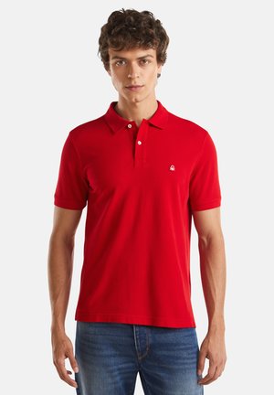 Camisa polo corta roja de algodón con cuello y tapeta de dos botones; presenta un pequeño logotipo bordado en el pecho.