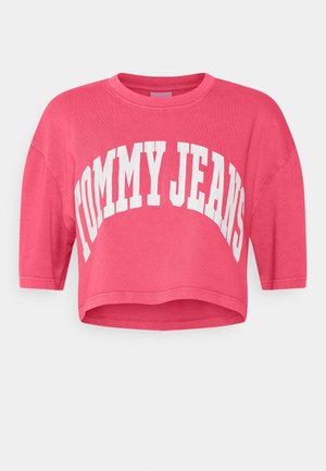 Kortærmet, cropped t-shirt i lyserødt bomuld med hvid "TOMMY JEANS" tekst foran i buet design.