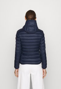 Marineblå pufferjakke med hætte, der har vandrette quiltede sektioner, en tætsiddende pasform og elastiske manchetter. Accentueret med et logo-lap.