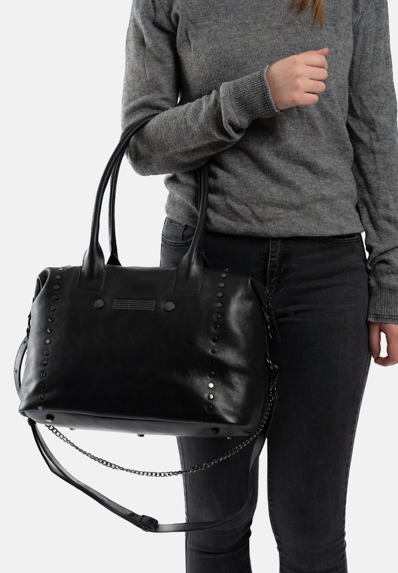 Zwarte faux leren handtas met ronde metalen studs, dubbele handvatten en een afneembare kettingriem. Gladde textuur en rechthoekige vorm.