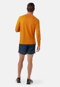 Valkoinen pitkähihaisen paita, joka on yhdistetty tummansinisiin kuviollisiin shortsihin, joissa on kevyt ja joustava kangas sekä rento istuvuus.