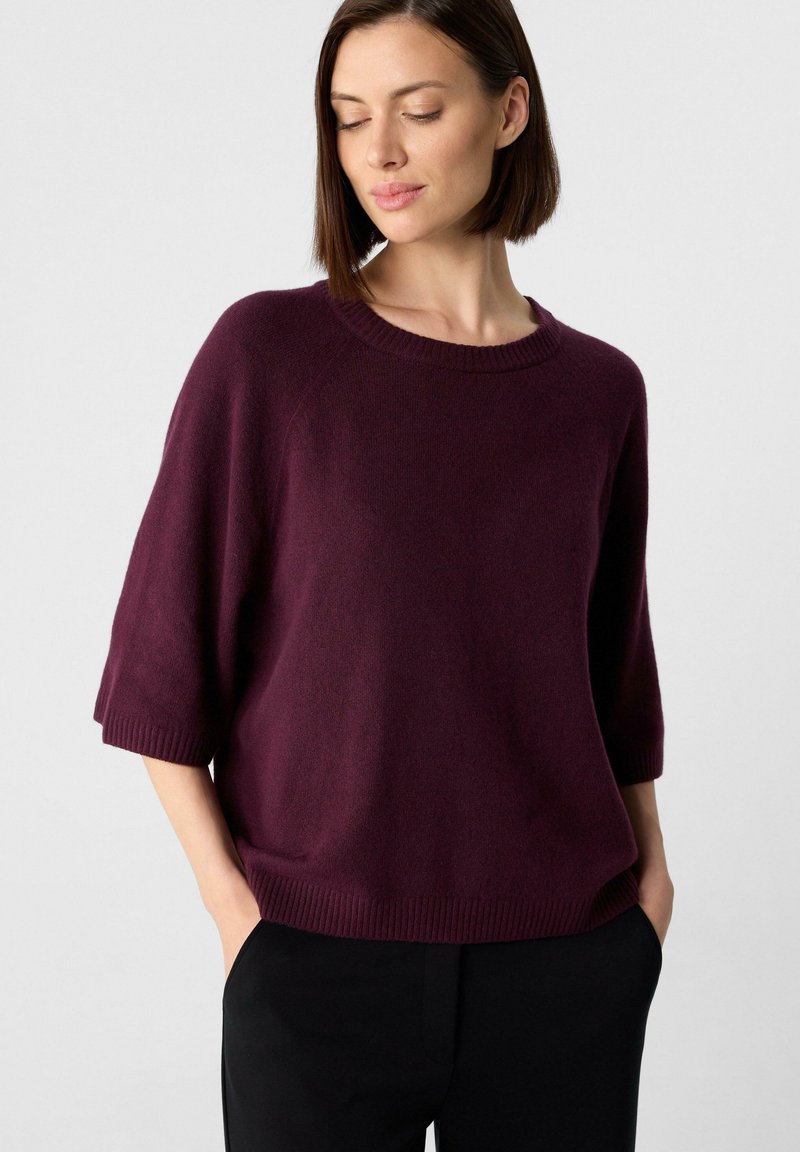 Burgunderfarbener Strickpullover mit rundem Ausschnitt, Dreiviertelärmeln und geripptem Saum; glatte Textur und lockere Passform.