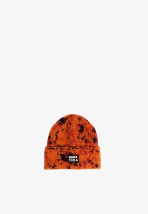Bonnet en tricot orange avec des taches noires, revers replié, et une étiquette noire avec du texte blanc. Texture douce, design à sommet arrondi.