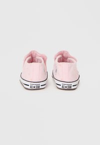 Różowe trampki z płótna z fakturowanym wykończeniem, wzorem w kropki i gumową podeszwą w czarno-białe akcenty. Widoczne logo Converse All Star.