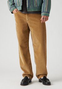 Pantalones de pana en un cálido color bronceado con acanalado vertical. Corte holgado, con un diseño clásico de cinco bolsillos y una cinturilla resistente.