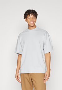Lys grå oversized t-shirt med rund hals og korte ærmer, lavet af bomuldsstof. Ingen mønstre eller synlige logoer.