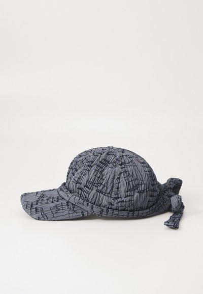 Gorra de color gris oscuro con textura y visera estructurada, que presenta un diseño arrugado y costuras de acento oscuras, terminada con un detalle atado en la parte posterior.
