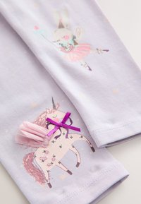 Levanduľová látka s motívom zajaca a jednorožca. Jednorožec má ružovú srsť s textilným doplnkom a detailom z fialovej stuhy.