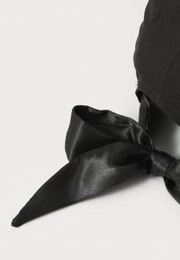Cappello nero con un fiocco in satin nero sul retro. Il tessuto appare liscio e il fiocco ha estremità appuntite, fornendo un accento elegante e dettagliato.