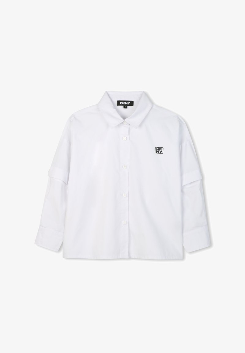 Camicia bianca a maniche lunghe con colletto button-down, caratterizzata da un piccolo logo DKNY nero sul petto. Realizzata in un tessuto liscio e leggero.