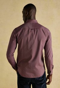 Rød- og hvidstribet langærmet skjorte med krave, knapmanchetter og buet kant, lavet af let stof med en glat tekstur.