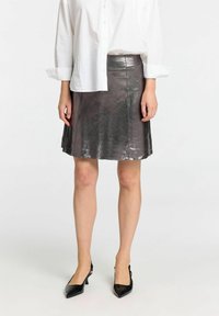 Metalisk grå læderskirt med en a-formet design, der har en glat tekstur og en talje. Kombinationen afsluttes med sorte hæle med spids tå.
