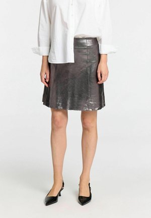 Metallisch grijze leren rok met een uitlopende ontwerp, met een gladde textuur en een tailleband. Gecombineerd met zwarte puntige hakken.
