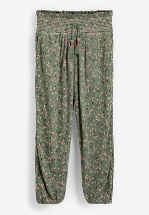 Pantalon ample à motif floral vert avec taille smockée élastique, cordon ajustable avec pompons et poignets élastiqués.