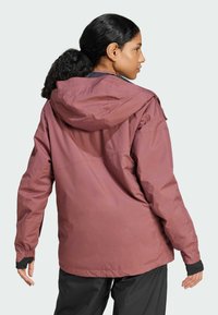 Vandtæt hættejakke i støvet rosa farve, med justerbare manchetter, en afslappet pasform og glat tekstur. Har en stor hætte og minimal detaljer.