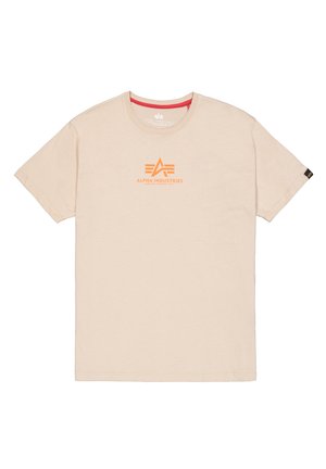 Bežové bavlněné tričko s krátkým rukávem a kulatým výstřihem. Uprostřed je oranžové logo "Alpha Industries" a červená výztuha u krku.