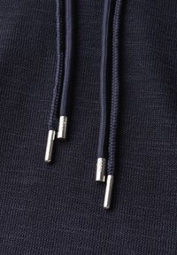 Navy blue hoodie fabric with a textured knit, featuring two braided drawstrings with metallic aglets for closure adjustment.