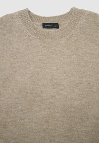 Beiger Strickpullover mit Rundhalsausschnitt. Weiche Textur, reguläre Passform und ein Etikett am Kragen mit der Größe L.