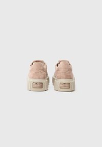 Pink suede platform sneakers with a textured beige sole, featuring a pull tab and small logo detail on the back.