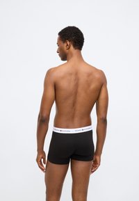 Boxer in cotone neri con vita bianca che presenta il logo "TOMMY HILFIGER". Materiale in cotone, design aderente, aperture per le gambe visibili.