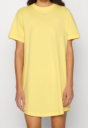 Robe t-shirt en coton jaune avec manches courtes, encolure ronde et petit logo blanc. Coupe droite, longueur mi-cuisse, texture lisse.