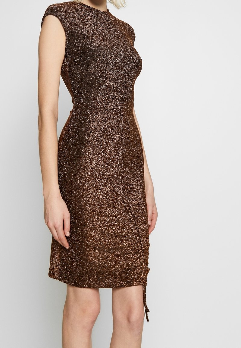 Brun, glittrig klänning med en figurnära design, korta ärmar och sidofästa detaljer. Den släta texturen förbättrar reflekterande egenskaper.