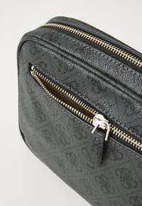 Borsa in tessuto nero con una finitura testurizzata e una cerniera color oro, dotata di una piccola tasca anteriore con una cerniera simile e un motivo con il logo.
