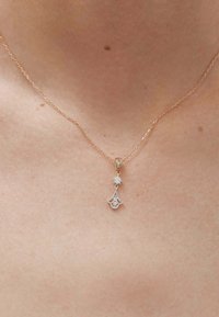 Collar de oro rosa con una cadena delicada, que presenta un colgante adornado con dos cristales redondos y un intrincado diseño floral.