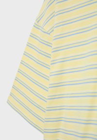 Gult stof med lyseblå og hvide vandrette striber, der viser et close-up af skulderen og ærmesømmen på en kortærmet skjorte.