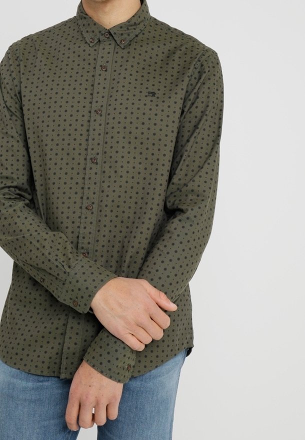 Zielona koszula zapinana na guziki w czarne kropki, wykonana z lekkiego materiału, z długimi rękawami i standardowym kołnierzykiem. Posiada małe logo na klatce piersiowej.