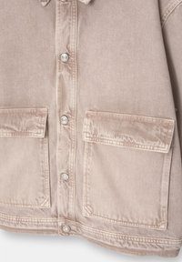 Beige denimjakke med klassisk krave, sølv farvede trykknapper og to forlommer; har en glat, let blank overflade.
