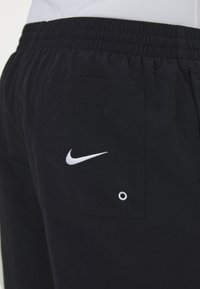 Navy Nike shorts yang menampilkan pinggang elastis, saku belakang dengan logo yang disulam, dan detail grommet logam. Tekstur yang halus.