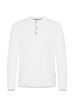 Balta garām piedurknēm krekls ar apaļu kakla izgriezumu, trīs pogu aizdari un kontrastējošu pelēku apdari pie piedurknēm un apakšmalas.