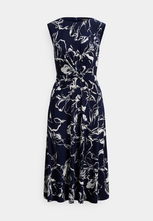 Mornarsko plava cvjetna haljina s bijelim uzorkom, bez rukava, s čvorom u struku i lepršavom suknjom. Izrađena od meke tkanine glatke teksture.