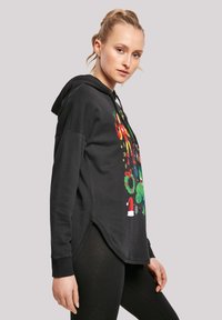 Felpa nera con cappuccio, impreziosita da grafiche colorate a tema festivo, maniche lunghe, una tasca a marsupio e orlo curvo. Tessuto morbido con vestibilità rilassata.
