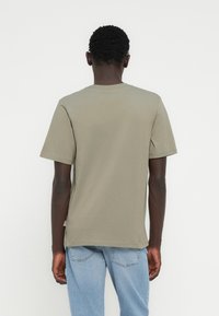 Λαδί βαμβακερό μπλουζάκι με κοντά μανίκια, λαιμόκοψη γύρω και ελαφριά υφή. Στο πίσω μέρος υπάρχει μια μικρή ετικέτα στο τελείωμα.