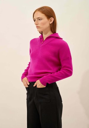 Maglione a maglia fucsia con scollo a V e cappuccio. Caratterizzato da polsini e orlo a coste. Abbinato a pantaloni neri a gamba larga. Texture liscia.