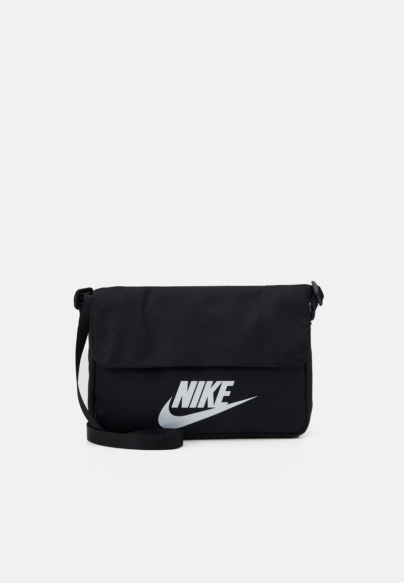 Melnas auduma sūtījumu soma ar atloku, kurai ir izteikta sudraba Nike zīme priekšpusē un regulējama siksna.