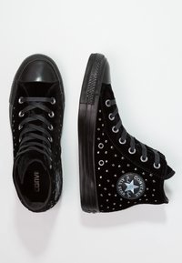 Svarta högsneakers i sammet med metallnitar och gummitå. Har grå snören och en rund logotyp-patch på sidan.