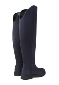 Un paio di stivali alti in suede blu navy con suole nere e bordi superiori leggermente scallopati, mostrati di profilo e da dietro.