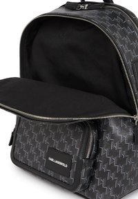 Rucsac negru cu un model geometric, având un compartiment principal cu fermoar și o pungă frontală, cu o textură de piele netedă.