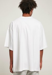 Hvid oversized bomulds T-shirt med sænkede skuldre og korte ærmer, med en rund hals og en glat overflade.