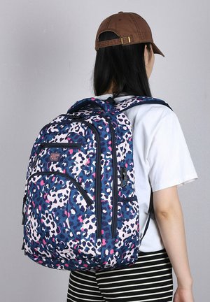 Blauwe luipaardprint rugzak met roze accenten, meerdere vakken, gevoerde schouderbanden en een duurzame stof. Draagbaar op de rug van een persoon.