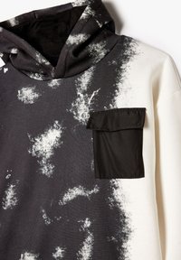 Hoodie in zwart en wit met een gespikkeld patroon. Voorzien van een zwarte stoffen zak aan de voorkant. Gemaakt van een katoenmix.